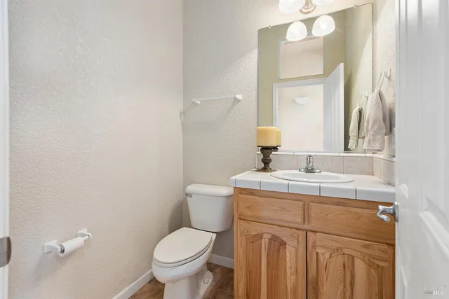 a bathroom with a toilet sink vanity and mirror