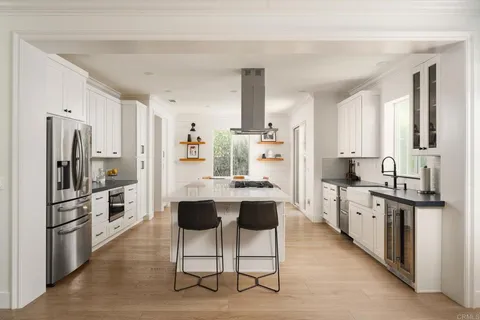 a room with stainless steel appliances kitchen island granite countertop a refrigerator and cabinets