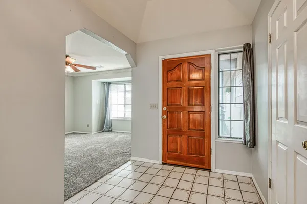 a view of an empty room with a ceiling fan and kitchen view