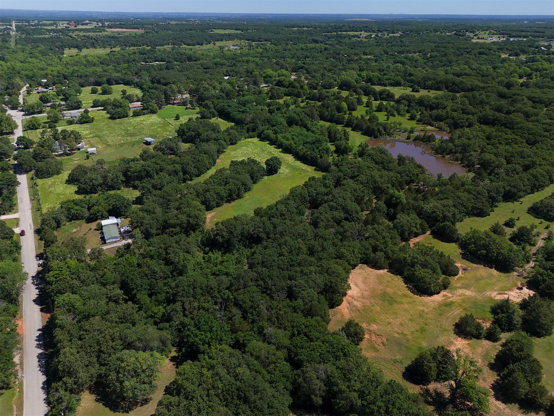 0 Harvey Road Ardmore, OK 73401 - Photo 5 of 10 Expansive rural landscape featuring a private pond, mature trees, and open grassy areas