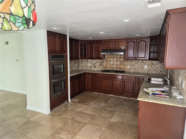 a kitchen with granite countertop wooden cabinets stainless steel appliances and a counter space