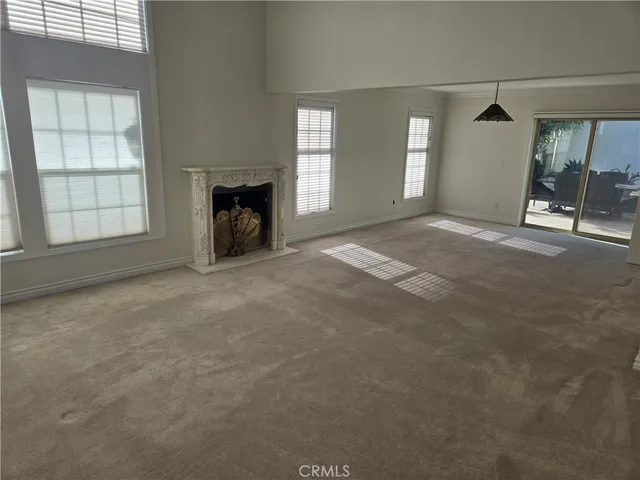 an empty room with windows and fireplace