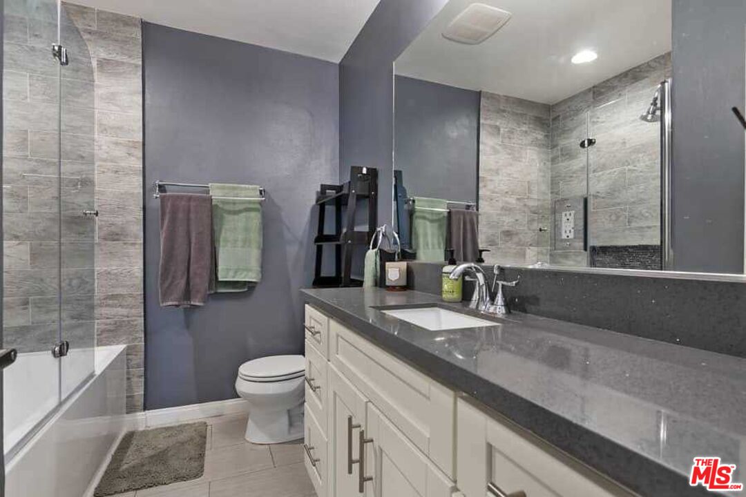 8460 Hatillo Avenue Winnetka, CA 91306 - Photo 13 of 19 a bathroom with a granite countertop sink a toilet a mirror and shower