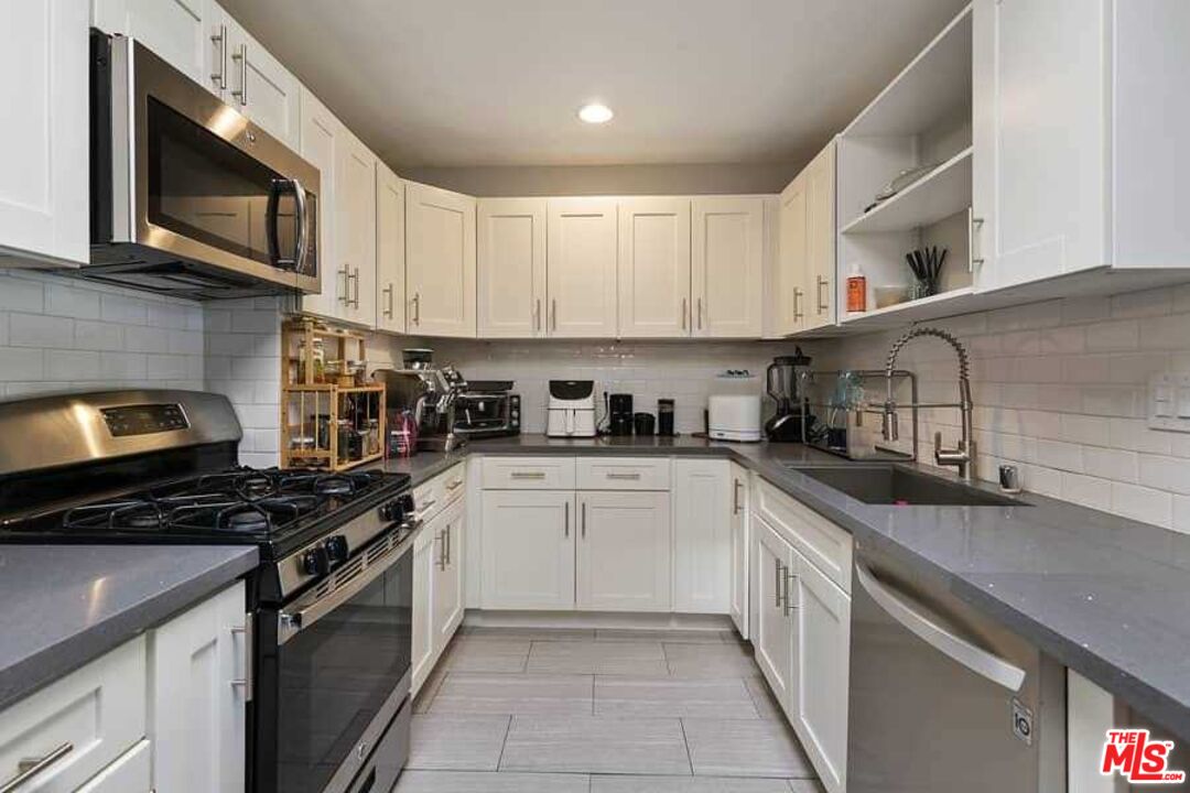 8460 Hatillo Avenue Winnetka, CA 91306 - Photo 4 of 19 a kitchen with stainless steel appliances granite countertop a sink stove microwave and cabinets