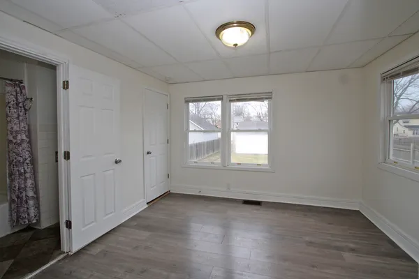 an empty room with wooden floor and windows