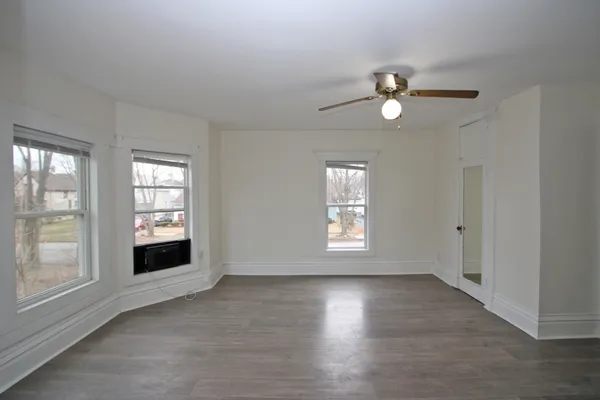 a view of an empty room with a window and wooden floor