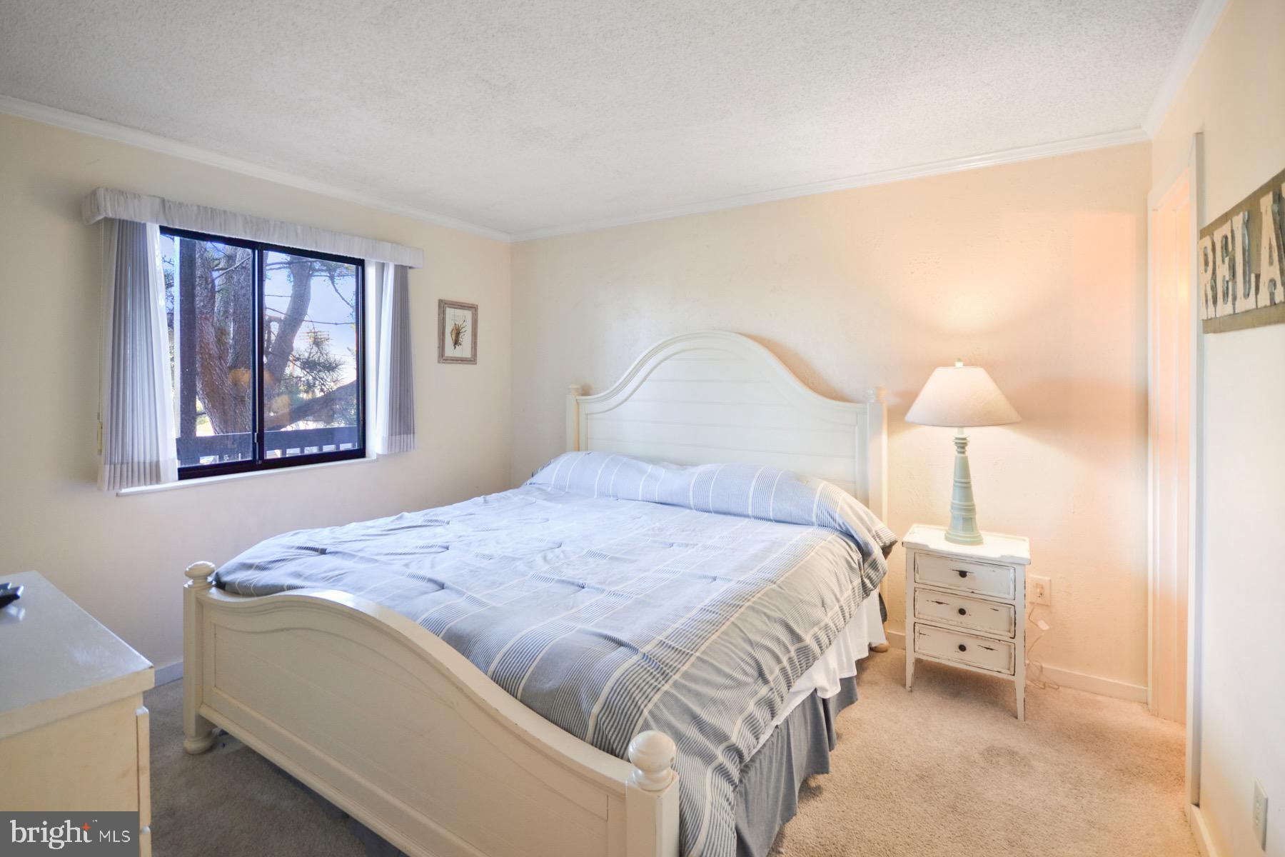 119 Old Landing Road, Unit 204J Ocean City, MD 21842 - Photo 12 of 35 a bedroom with a bed and a lamp