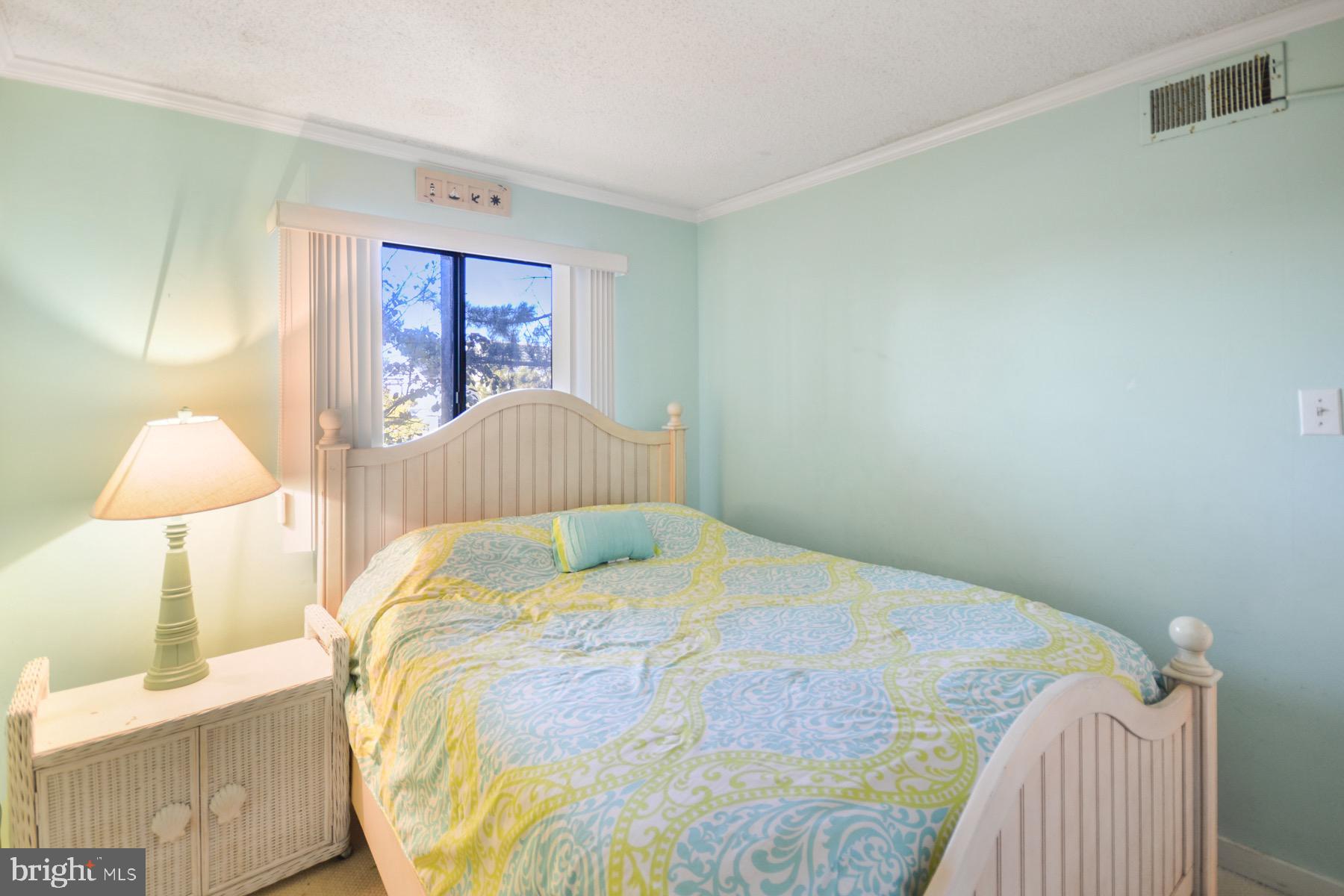 119 Old Landing Road, Unit 204J Ocean City, MD 21842 - Photo 19 of 35 a bedroom with a bed and a lamp