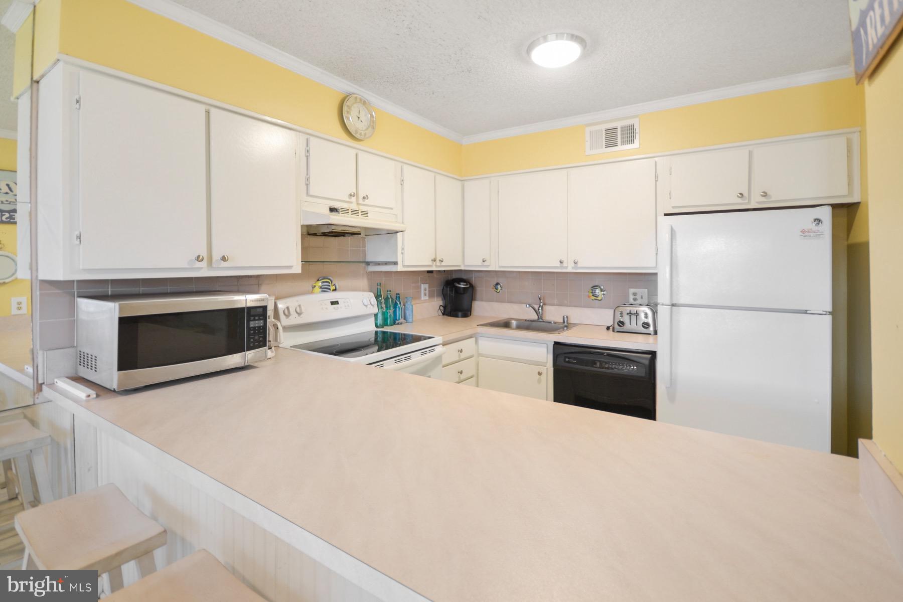 119 Old Landing Road, Unit 204J Ocean City, MD 21842 - Photo 2 of 35 a kitchen with a refrigerator sink and white cabinets