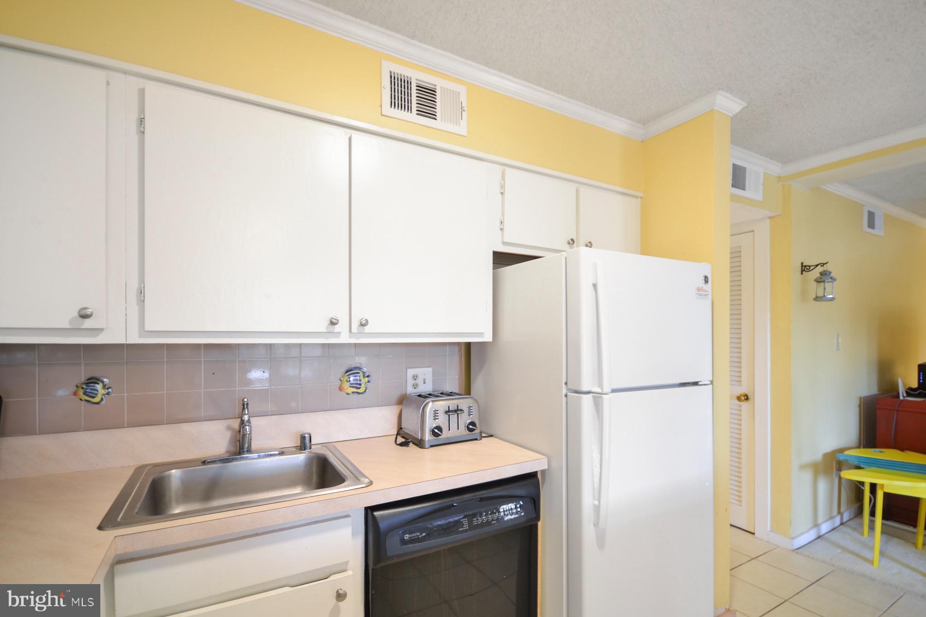119 Old Landing Road, Unit 204J Ocean City, MD 21842 - Photo 4 of 35 a kitchen with a sink a refrigerator and cabinets