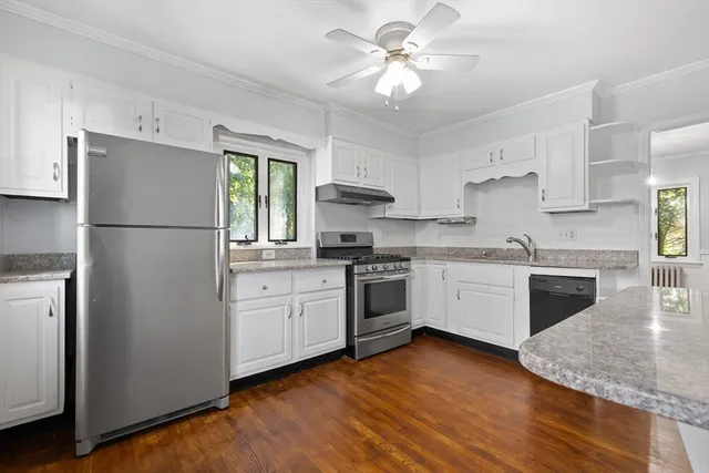 a kitchen with stainless steel appliances granite countertop a refrigerator a stove a sink and white cabinets