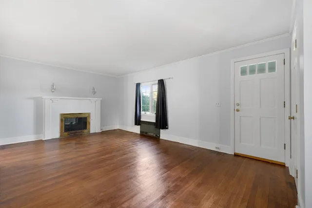an empty room with wooden floor fireplace and windows