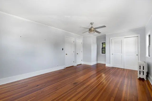 an empty room with wooden floor and a ceiling fan