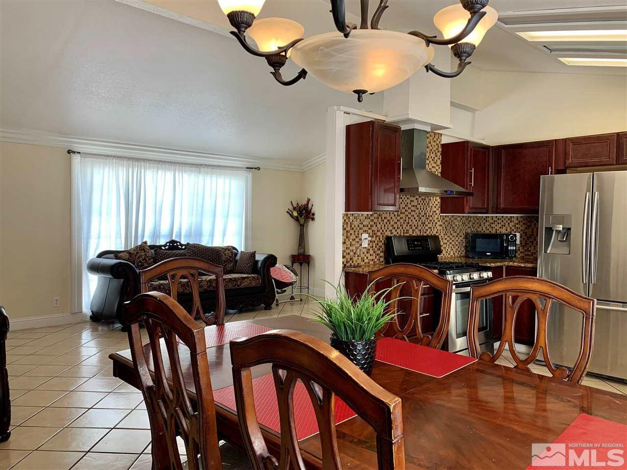 2182 Barberry Way Reno, NV 89512 - Photo 4 of 12 a kitchen with stainless steel appliances granite countertop a stove top oven a refrigerator a dining table and chairs with wooden floor