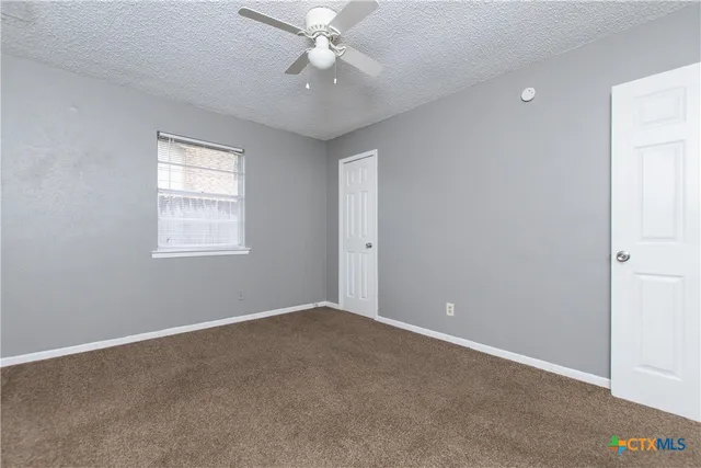 an empty room with windows and fan