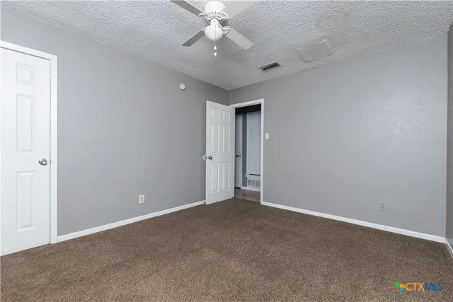 an empty room with a chandelier fan and windows
