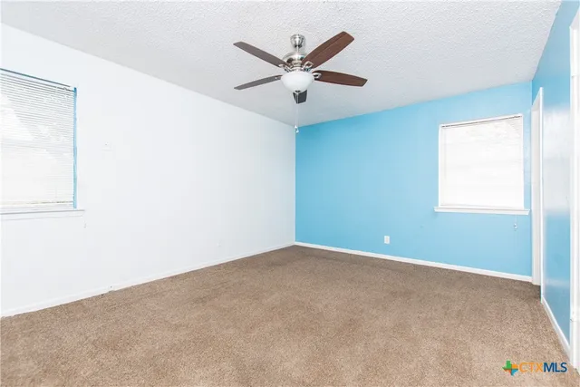 an empty room with ceiling fan and window
