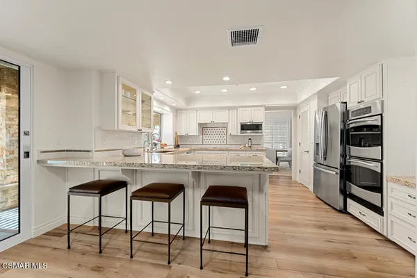 a kitchen with cabinets stainless steel appliances and wooden floor