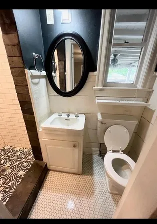 a bathroom with a toilet mirror vanity and a sink