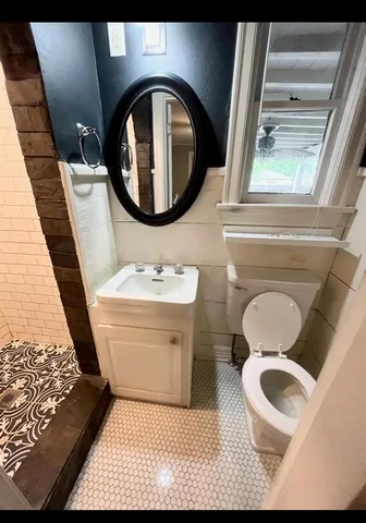 a bathroom with a toilet mirror vanity and a sink
