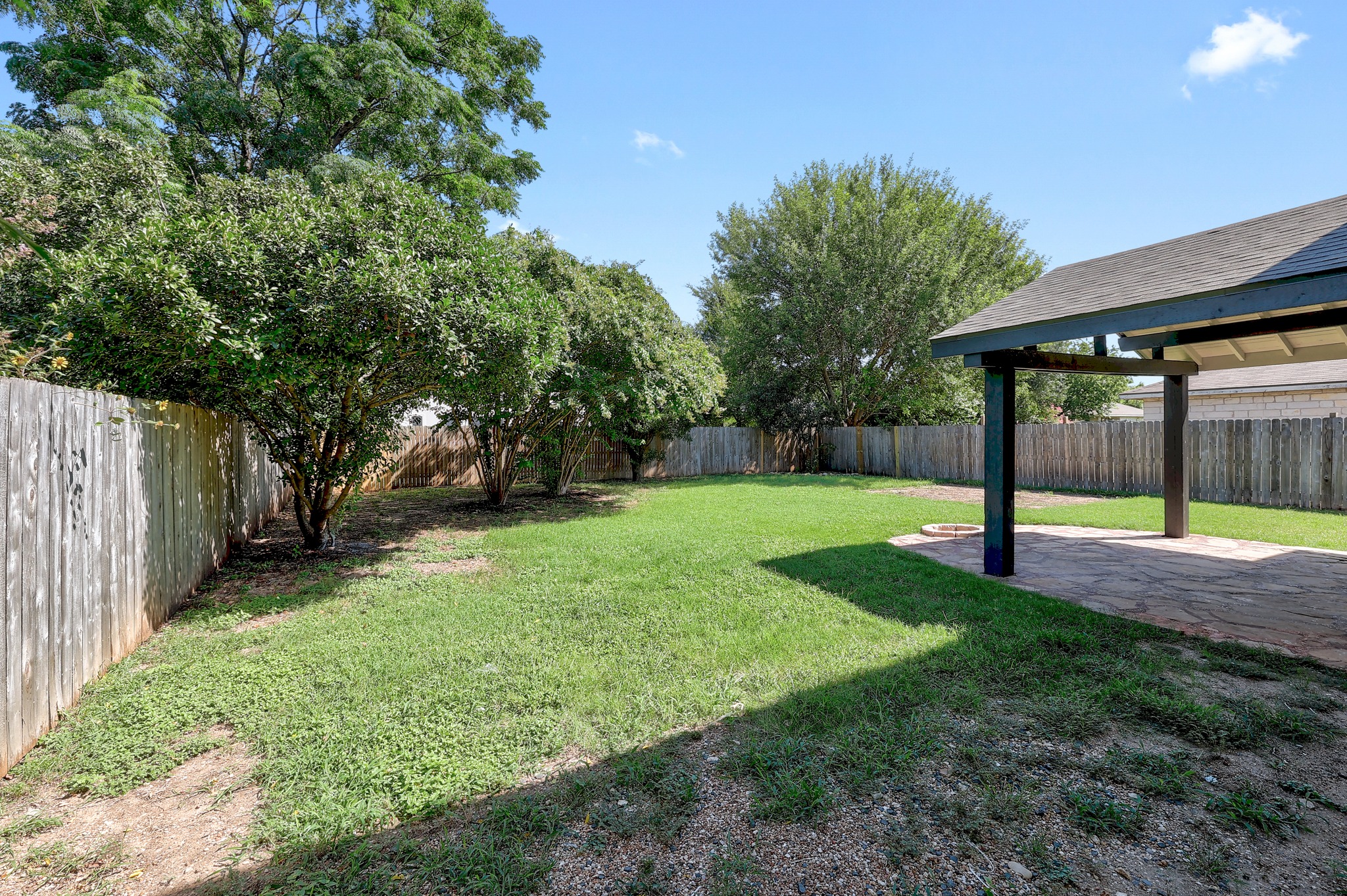 709 Los Robles Road Leander, TX 78641 - Photo 4 of 26 A spacious, fenced backyard offers a verdant lawn and a welcoming covered patio.