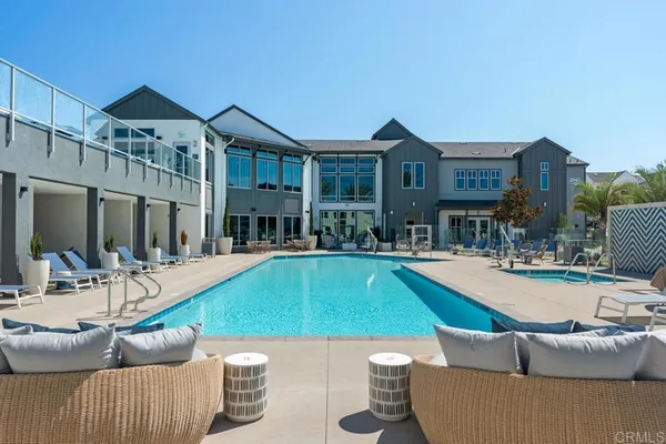 a view of swimming pool with outdoor seating and house in the background