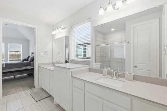 a bathroom with a sink double vanity granite tub shower and a mirror