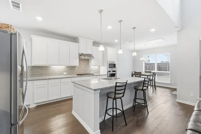 a kitchen with stainless steel appliances kitchen island granite countertop a table chairs sink and cabinets