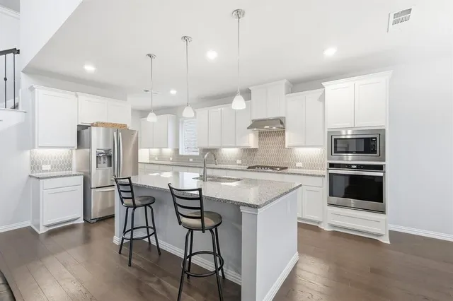 a kitchen with a refrigerator a stove a sink and chairs