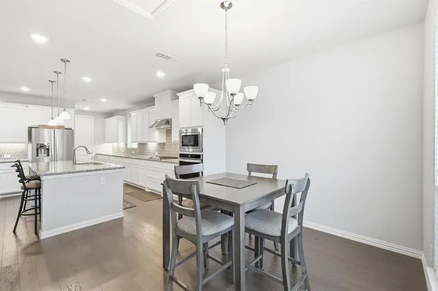 a dining room filled chandelier and kitchen view