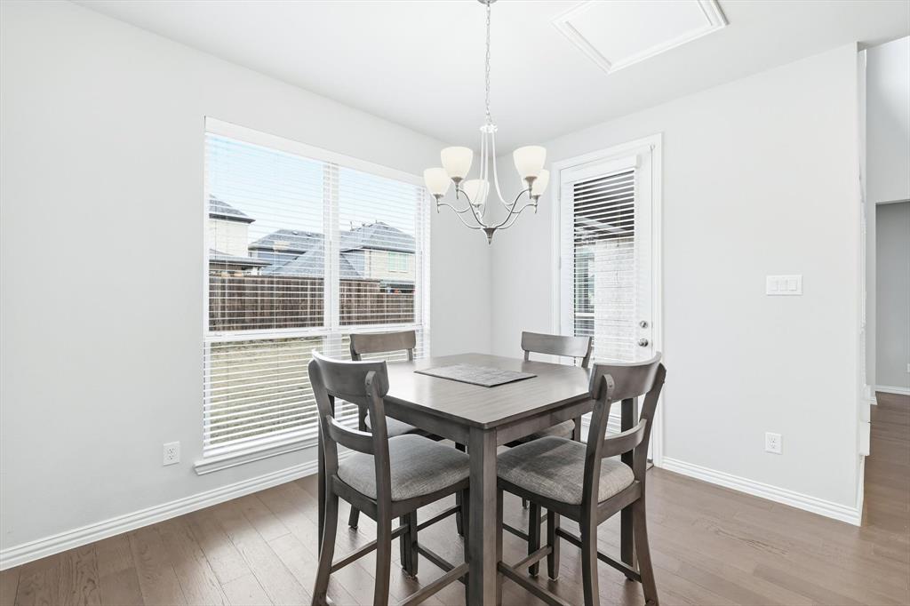 1708 Bird Cherry Lane Prosper, TX 75078 - Photo 7 of 32 a dining room with wooden floor a chandelier a wooden table and chairs