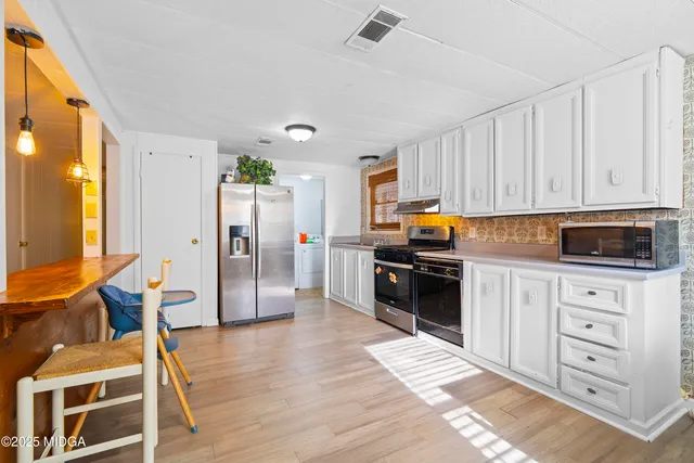 a kitchen with stainless steel appliances granite countertop a refrigerator a stove and a sink