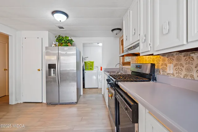 a kitchen with stainless steel appliances granite countertop a stove a sink dishwasher and cabinets with wooden floor