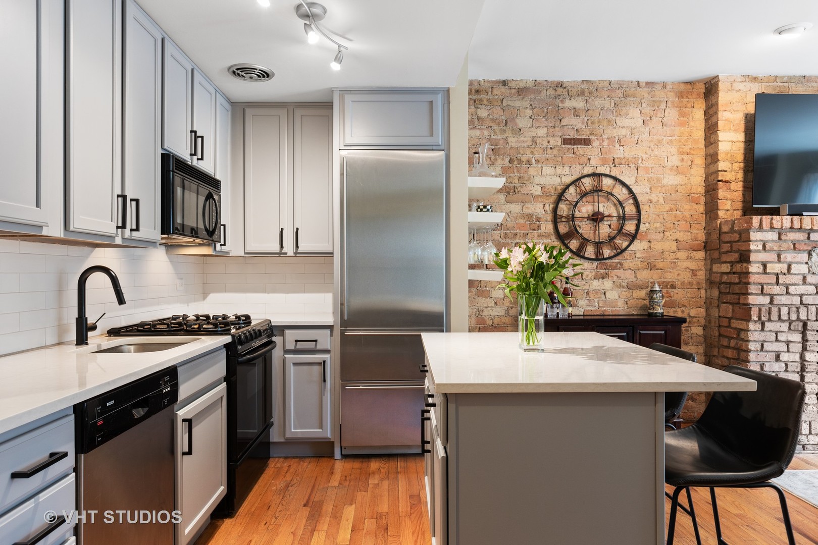 2956 North Halsted Street, Unit 2 Chicago, IL 60657 - Photo 7 of 13 a kitchen with stainless steel appliances granite countertop a sink a stove and a wooden floors