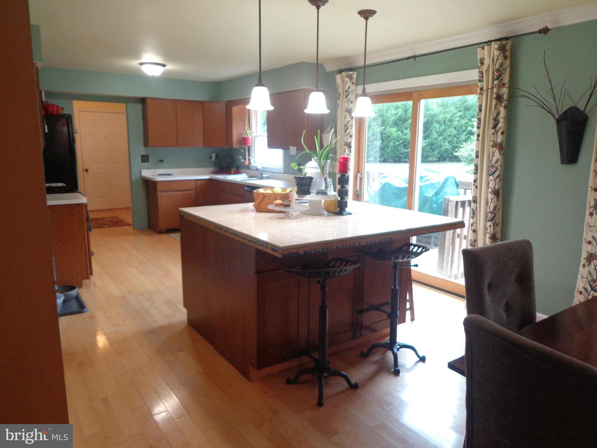 9323 Settle School Road Rixeyville, VA 22737 - Photo 20 of 30 a kitchen with stainless steel appliances granite countertop a sink a stove a refrigerator a dining table and chairs with wooden floor