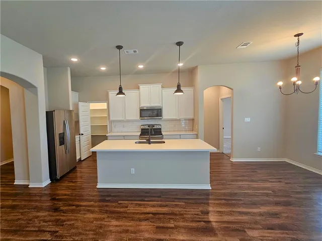 a view of a kitchen with kitchen island a counter top space a sink appliances and cabinets