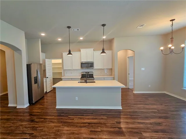 a view of a kitchen with kitchen island a counter top space a sink appliances and cabinets