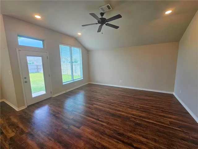 an empty room with wooden floor and windows