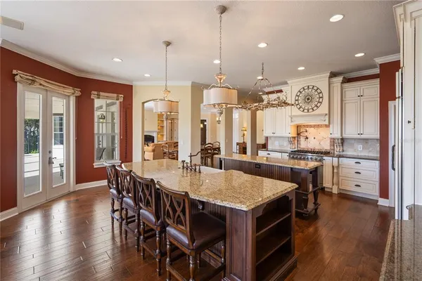 a large kitchen with stainless steel appliances granite countertop a stove and a view of living room