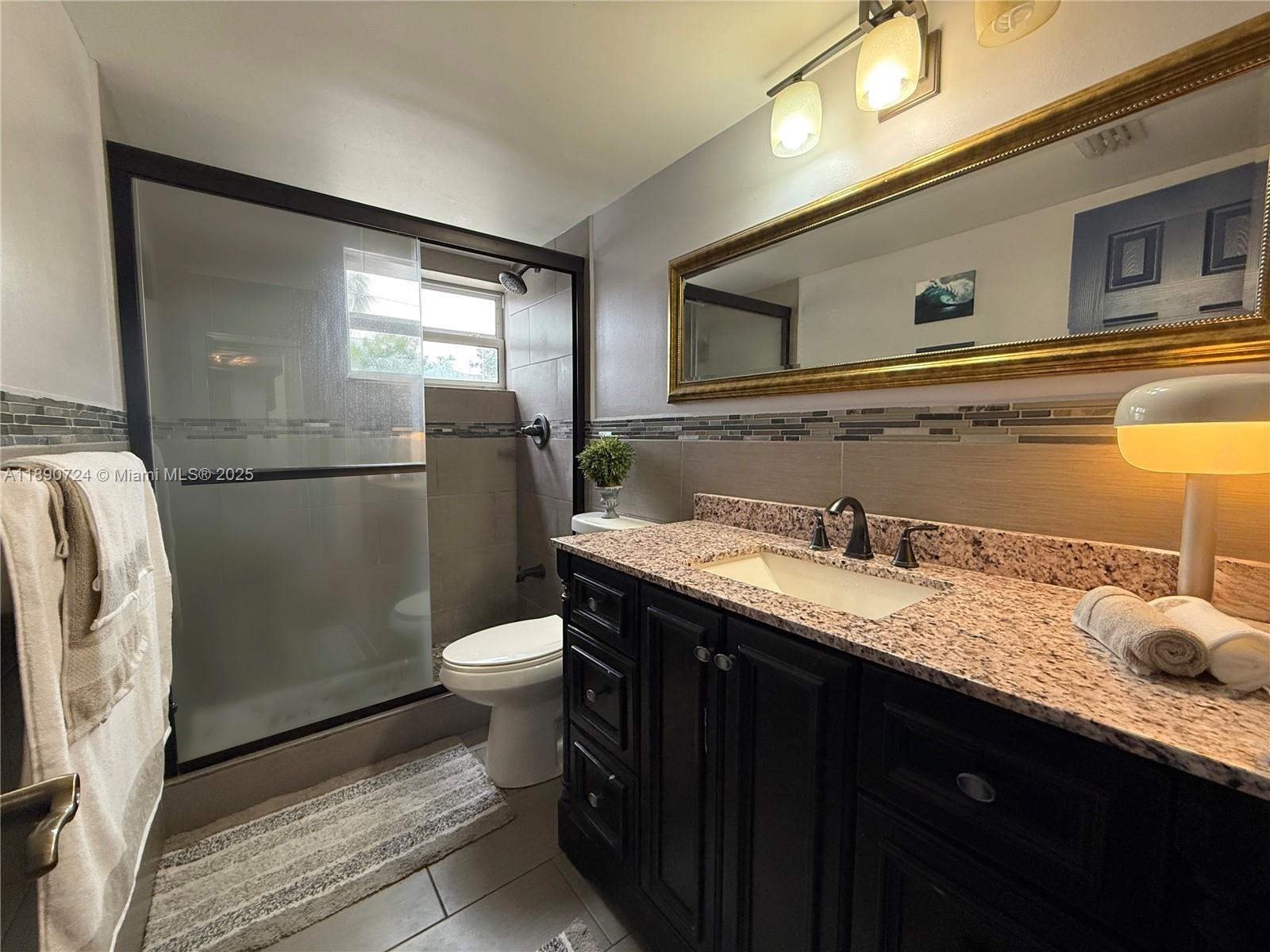 801 Meridian Avenue, Unit 1A Miami Beach, FL 33139 - Photo 8 of 18 a bathroom with a granite countertop sink toilet and shower