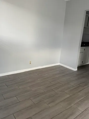 a view of an empty room with wooden floor and a flat screen tv