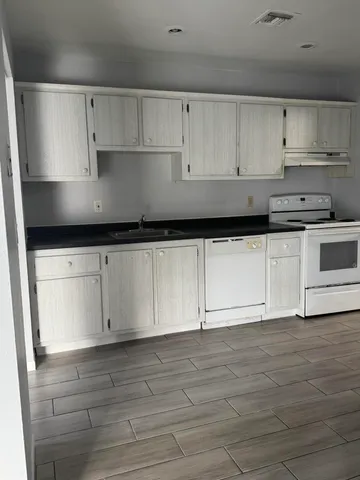 a kitchen with granite countertop white cabinets and stainless steel appliances
