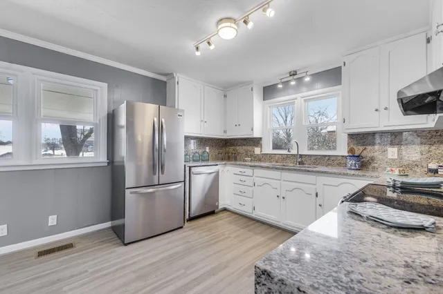 a kitchen with granite countertop a refrigerator stove and sink