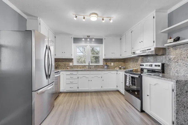 a kitchen with a refrigerator stove and white cabinets