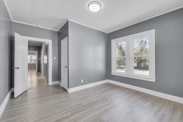 an empty room with wooden floor and windows
