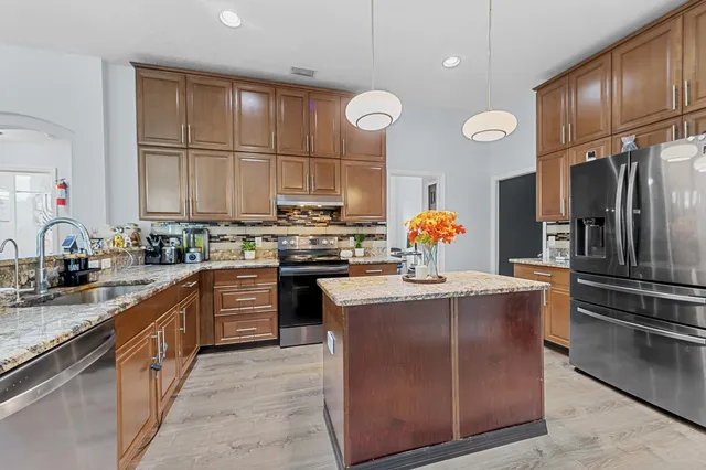 a kitchen with stainless steel appliances granite countertop a sink stove and refrigerator