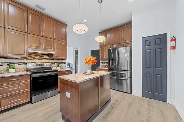 a kitchen with stainless steel appliances granite countertop a refrigerator a stove a sink and a refrigerator