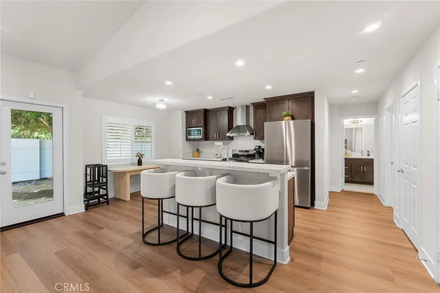 a kitchen with stainless steel appliances a dining table chairs refrigerator and cabinets