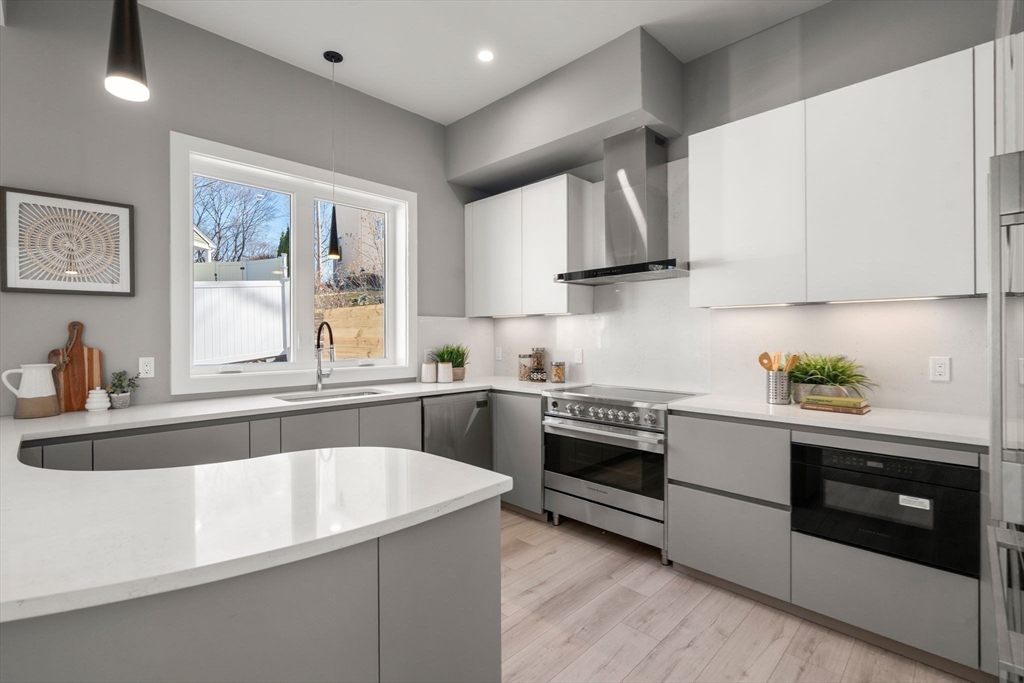 28 Wilson Circle, Unit 28 Newton, MA 02461 - Photo 7 of 14 a kitchen with stainless steel appliances granite countertop white cabinets a sink a stove a microwave and wooden floors