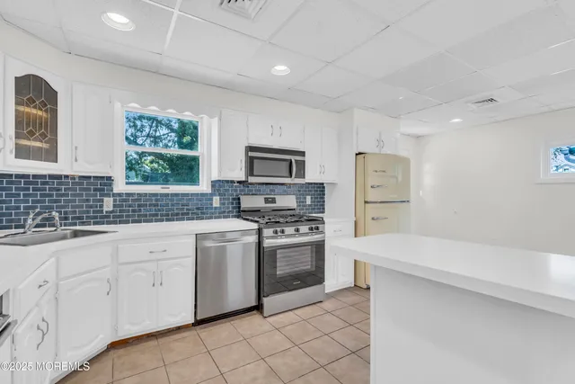 a kitchen with white cabinets and appliances